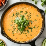 Overhead view of smoked queso dip served in a cast iron skillet on white marble, garnished with cilantro and surrounded by tortilla chips.