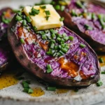 Roasted purple sweet potatoes served on a rustic plate, topped with chives, honey drizzle, and butter, placed in a modern kitchen with white marble countertops.